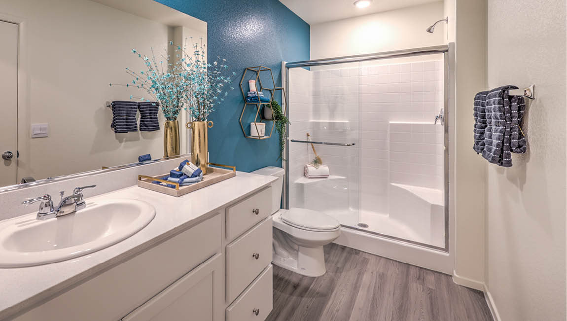 Attached to the Bedroom One Suite, our 1430 model bathroom with granite countertops at the Bath Vanity, a walk-in shower, mirror, and white cabinets.