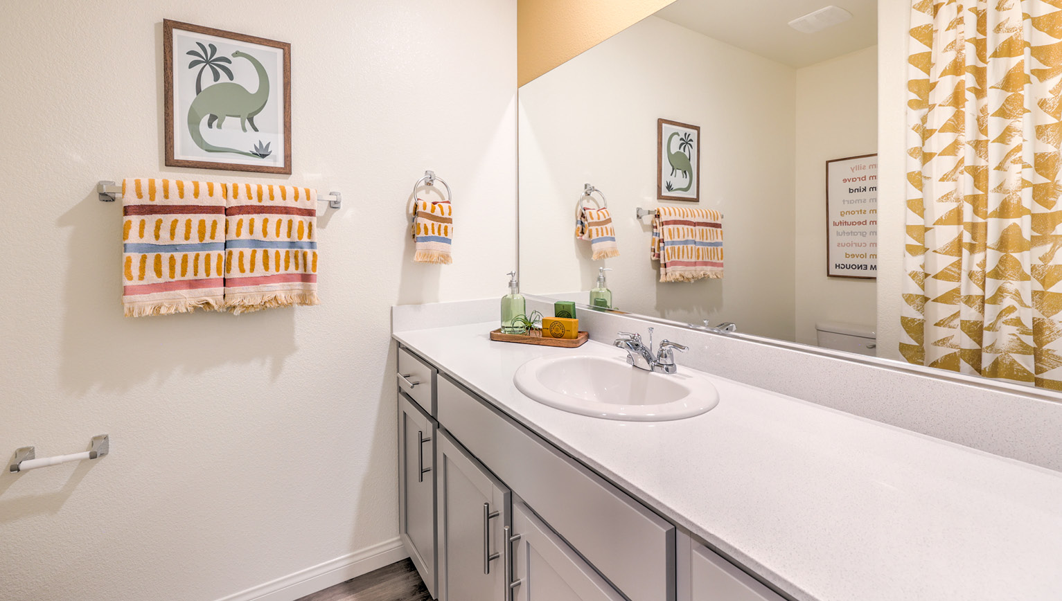 Bathroom Two in our Kalea Bay 1865 model with quartz/marble fusion countertops at the Bath Vanity, a walk-in shower, mirror, and grey cabinets.
