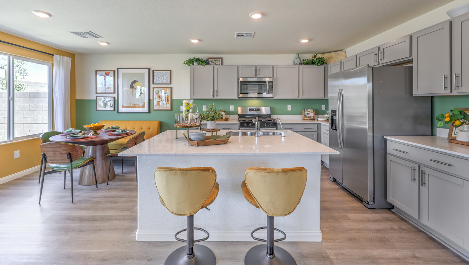 Our 1865 model kitchen in the Kalea Bay Community with grey shaker style cabinets, quartz countertops, a kitchen island, and Whirlpool Stainless Steel appliances.