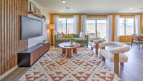 open floor concept. Great room with a couch, two lounging chairs, entertainment center and television