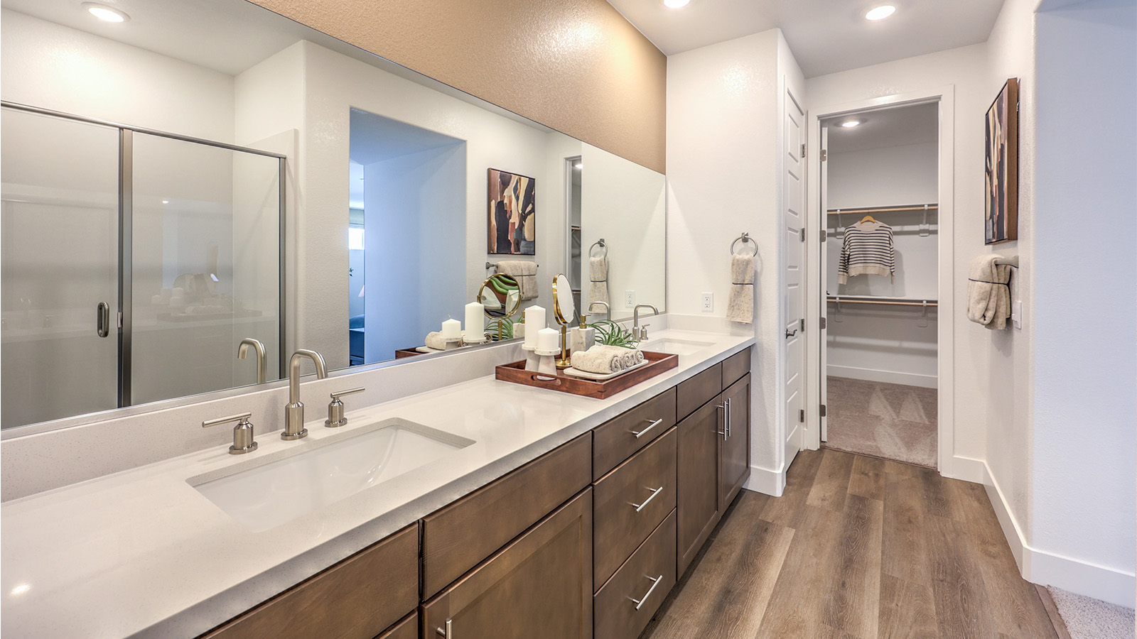 Attached to the Bedroom One Suite, our 3000 model bathroom with granite countertops at the double Bath Vanity, a walk-in shower, walk-in closet, linen closet, mirror, and white cabinets.