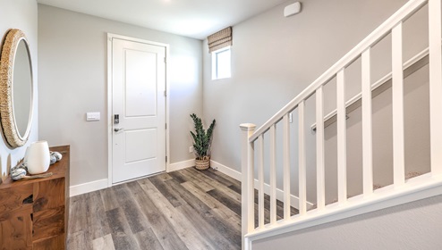 The front door entrance to our Heartland Falls 3001 model with a table and mirror, adjacent to the stairs.