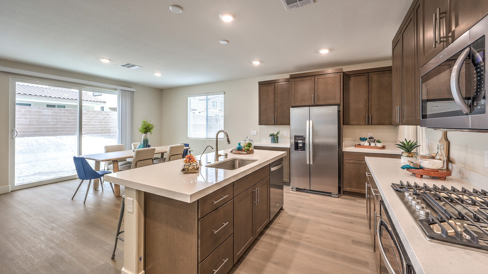 Our 2436 model kitchen in the Heartland Falls Community with brown shaker style cabinets, Quartz Slab countertops, a kitchen island, and Whirlpool Stainless Steel appliances.