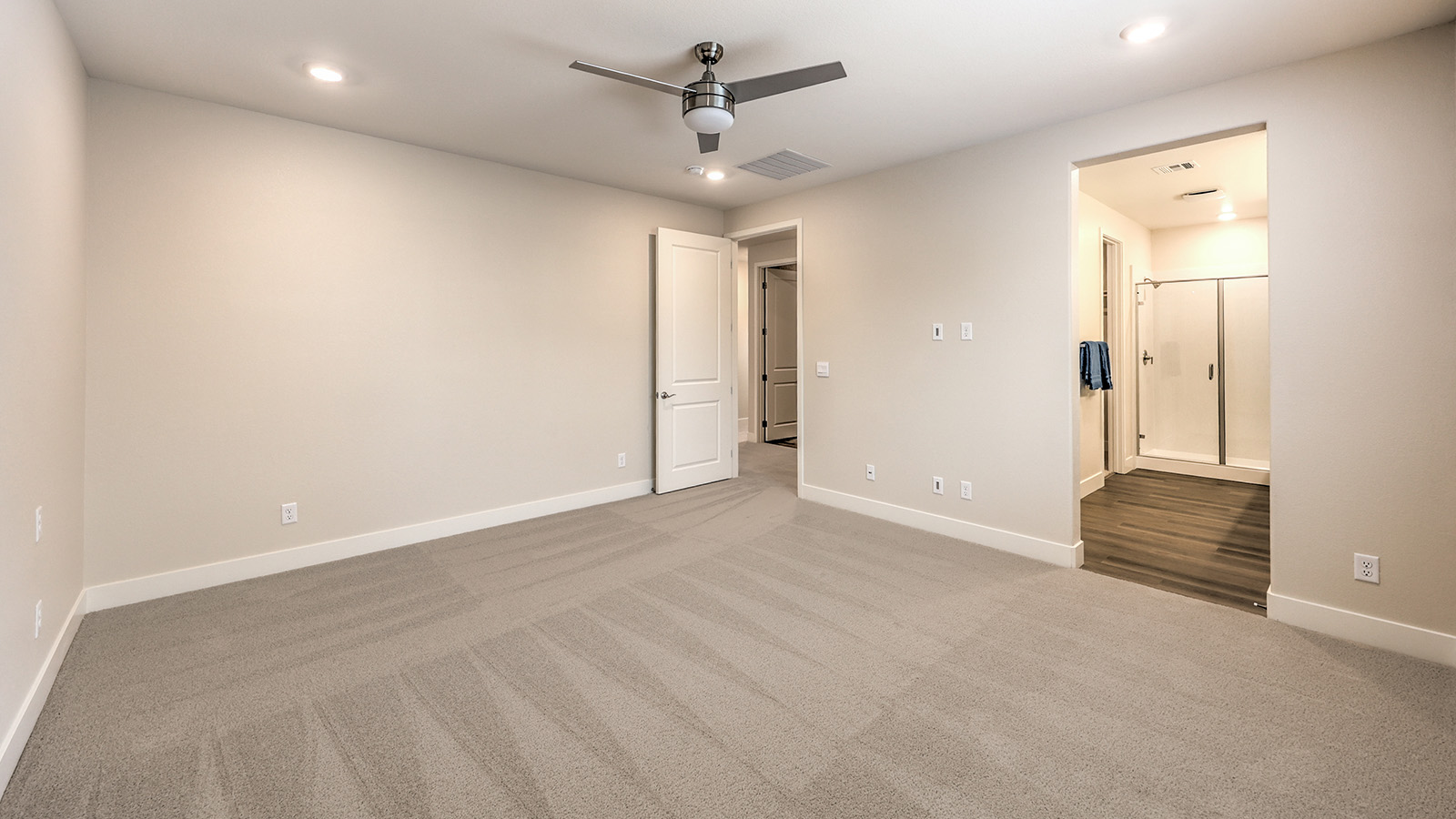The Bedroom One Suite in our Heartland Falls 2436 model with carpet flooring, recessed ceiling lights, and a window.