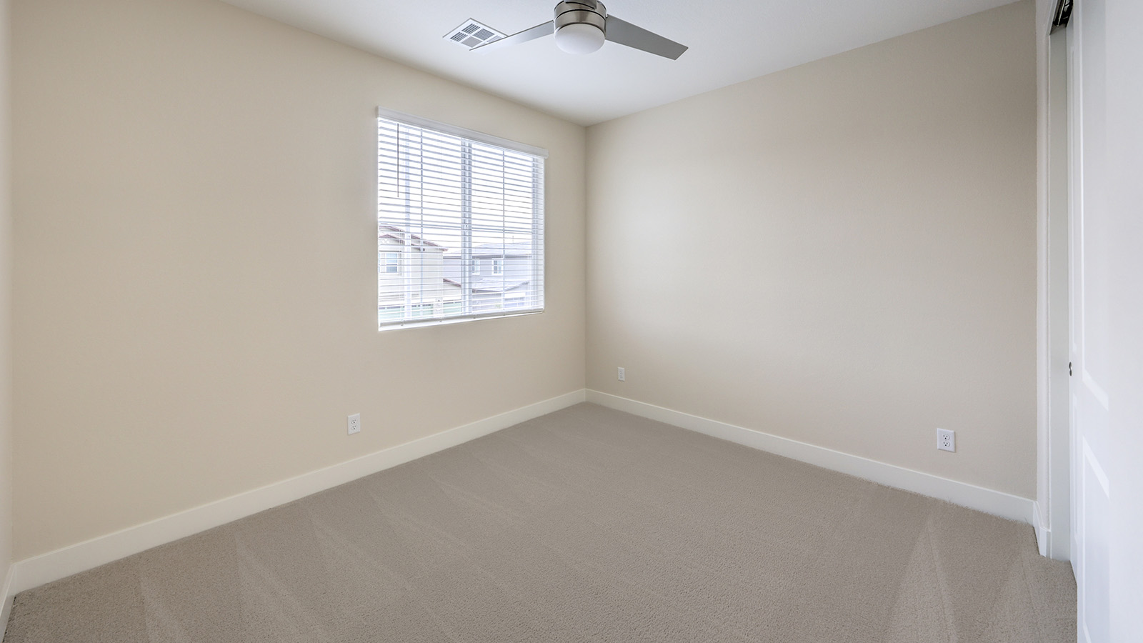 Bedroom Two in our Heartland Falls 2436 model with carpet flooring, a sliding closet, and one window.