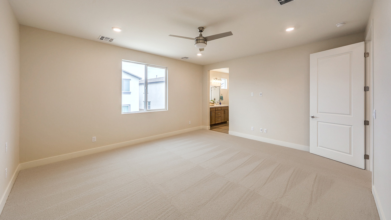 The Bedroom One Suite in our Heartland Falls 2660 model with carpet flooring, ceiling fan with a light kit, and large windows.