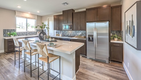 Our 3001 model kitchen in the Heartland Falls Community with white shaker style cabinets, Granite Slab countertops, a kitchen island, window, and Whirlpool Stainless Steel appliances.