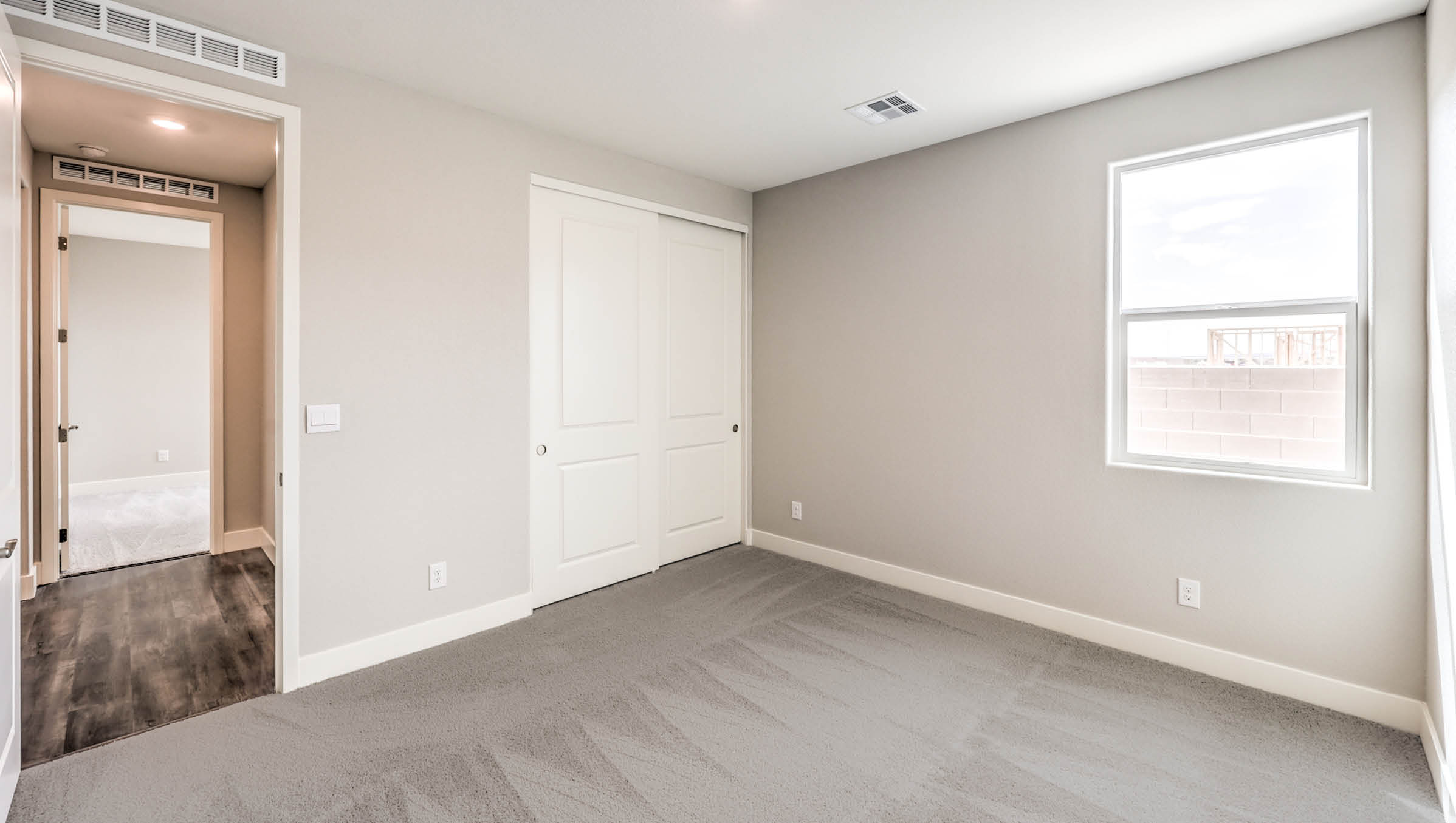 The Heartland Manor 2300 Plan Bedroom 3 featuring plush wall-to-wall carpet, a wide window for natural light, and a double-door closet for convenient storage. This versatile room offers a comfortable layout suitable for a guest room, children’s room, or home office.