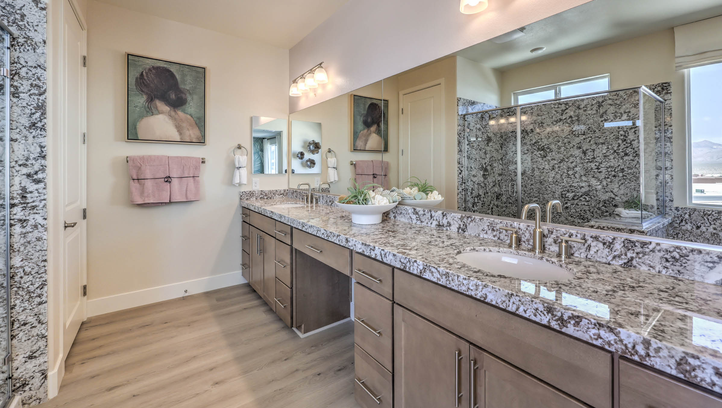 Attached to the Bedroom One Suite, our 4425 model bathroom with granite countertops at the double Bath Vanity, a walk-in closet, mirror, and brown cabinets.