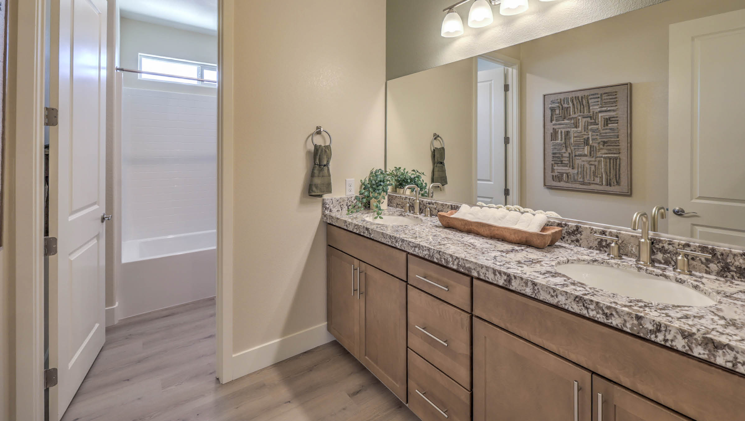 Bathroom Three in our Heartland Summit 4425 model with granite countertops at the double Bath Vanity, a walk-in shower, mirror, and brown cabinets.