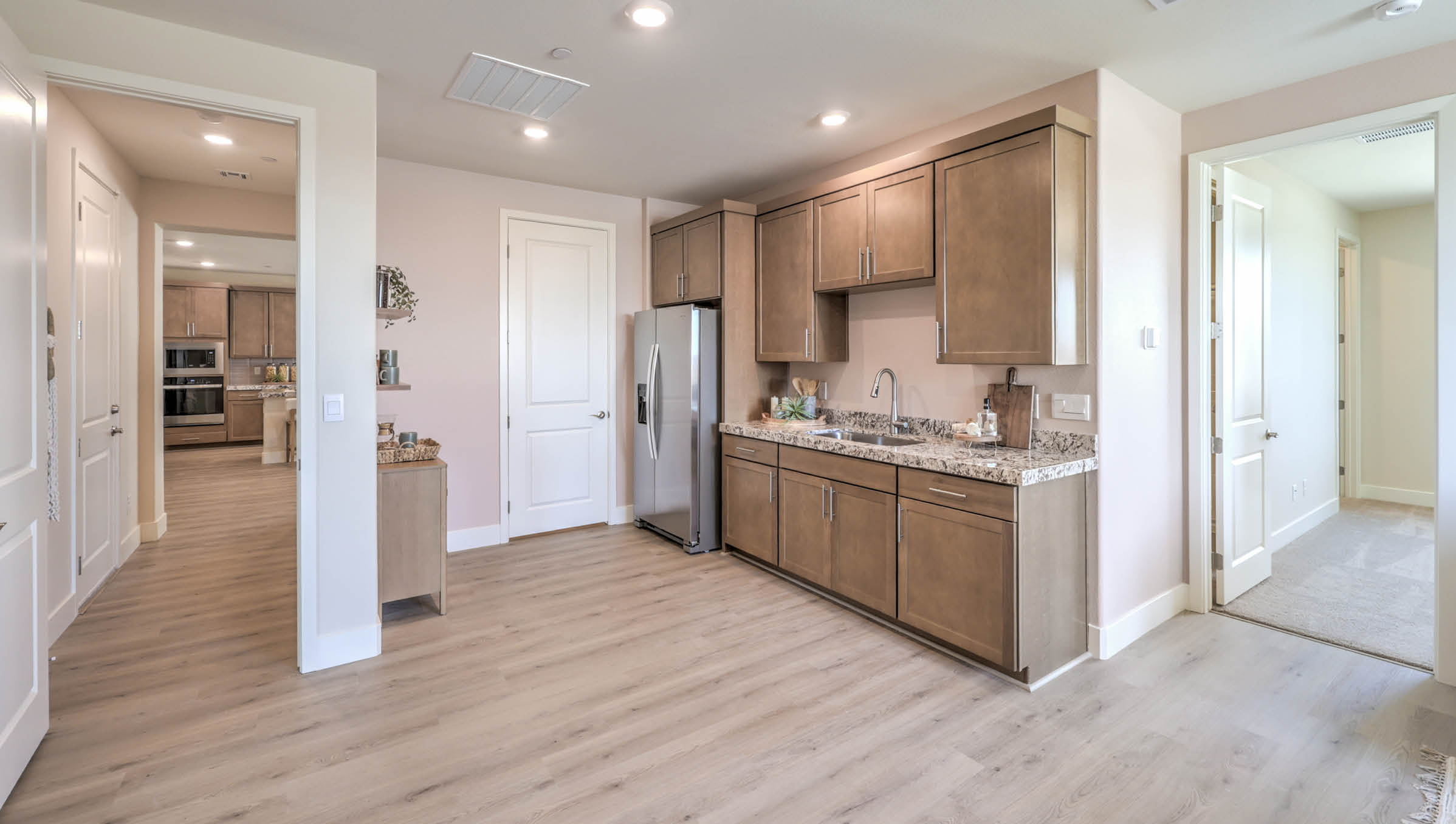 Our Heartland Summit 4425 Multigen with a Whirlpool stainless steel refrigerator, sink, shaker style cabinets, and quartz countertops.