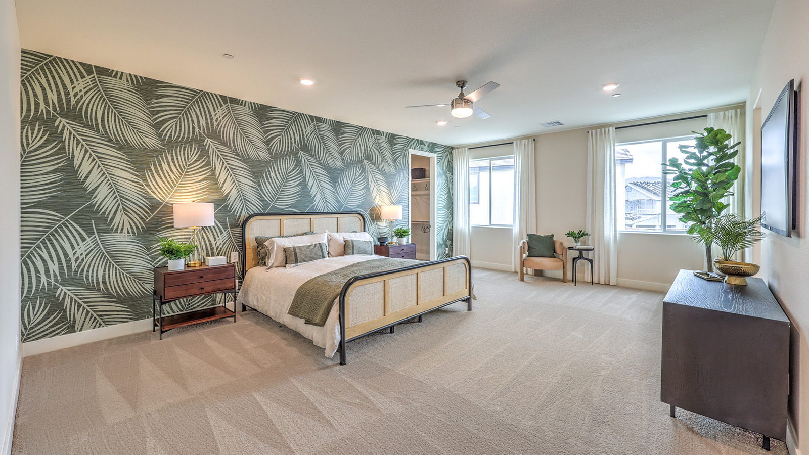 The Bedroom One Suite in our Heartland Summit 4425 model with carpet flooring, large windows, and a ceiling fan with a light kit.