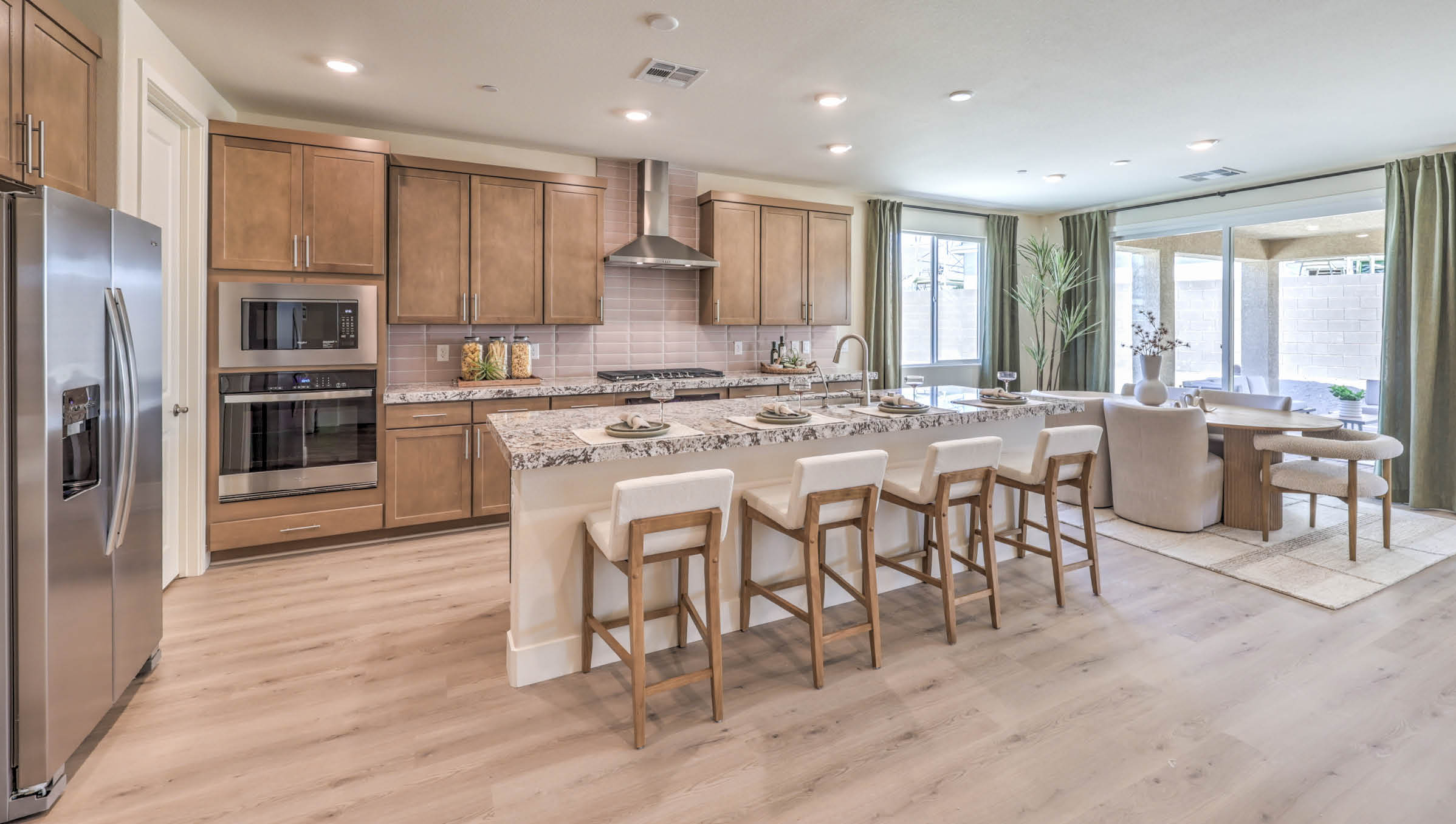 Our 4425 model kitchen in the Heartland Summit Community with brown shaker style cabinets, quartz countertops, a kitchen island, 5-burner cooktop, large pantry, and Whirlpool Stainless Steel appliances.