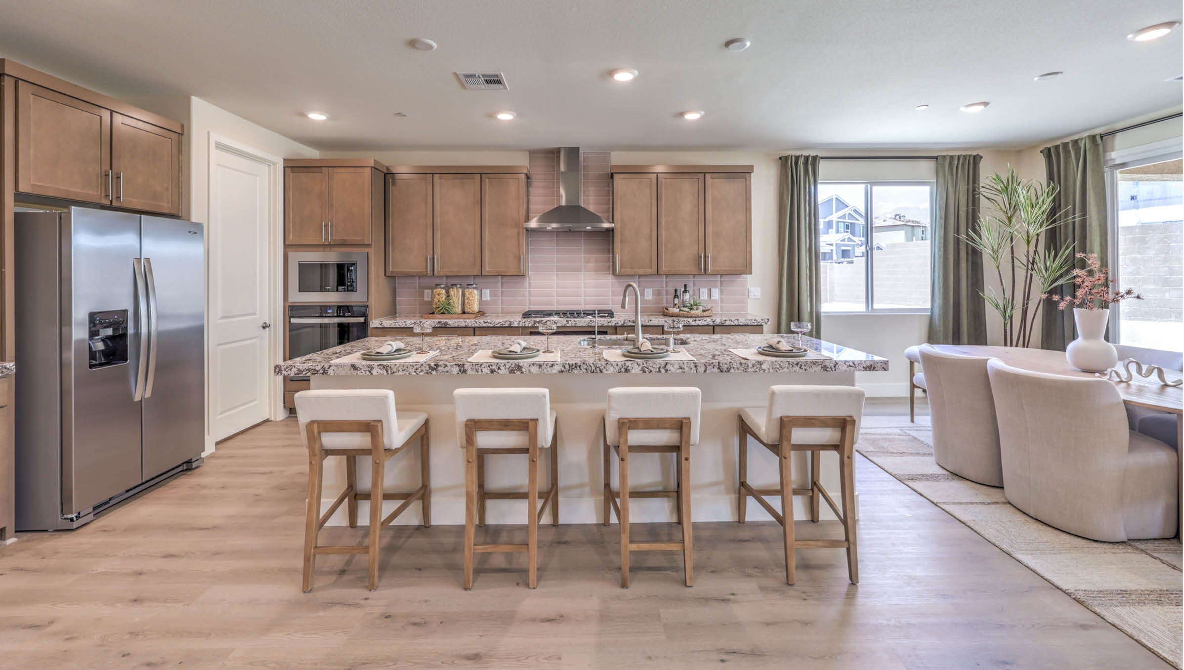 Our 4425 model kitchen in the Heartland Summit Community with brown shaker style cabinets, quartz countertops, a kitchen island, 5-burner cooktop, large pantry, and Whirlpool Stainless Steel appliances.