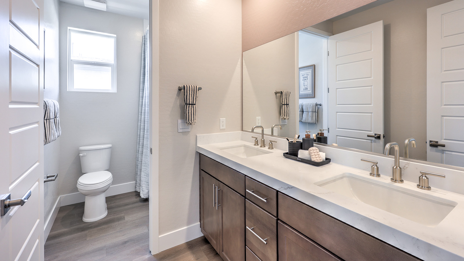 Bathroom Two in our Heartland Summit 4418 model with granite countertops at the double Bath Vanity, a walk-in shower, mirror, and brown cabinets.