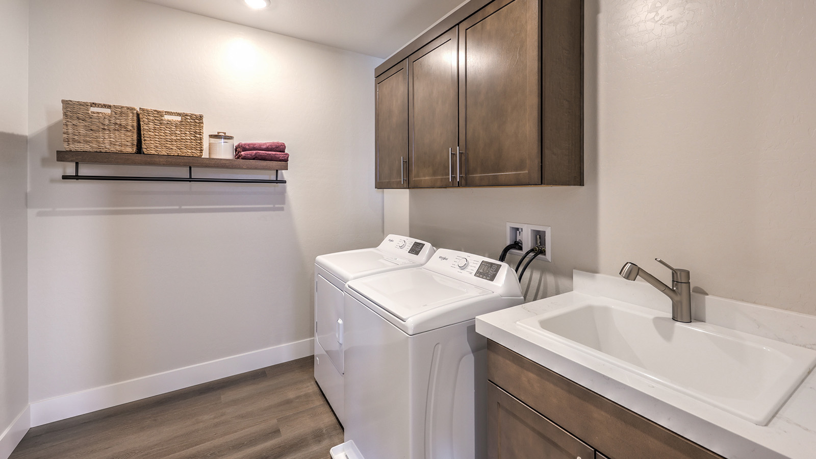 Our Heartland Summit 4418 model laundry room with brown shaker style cabinets and a washer and dryer.