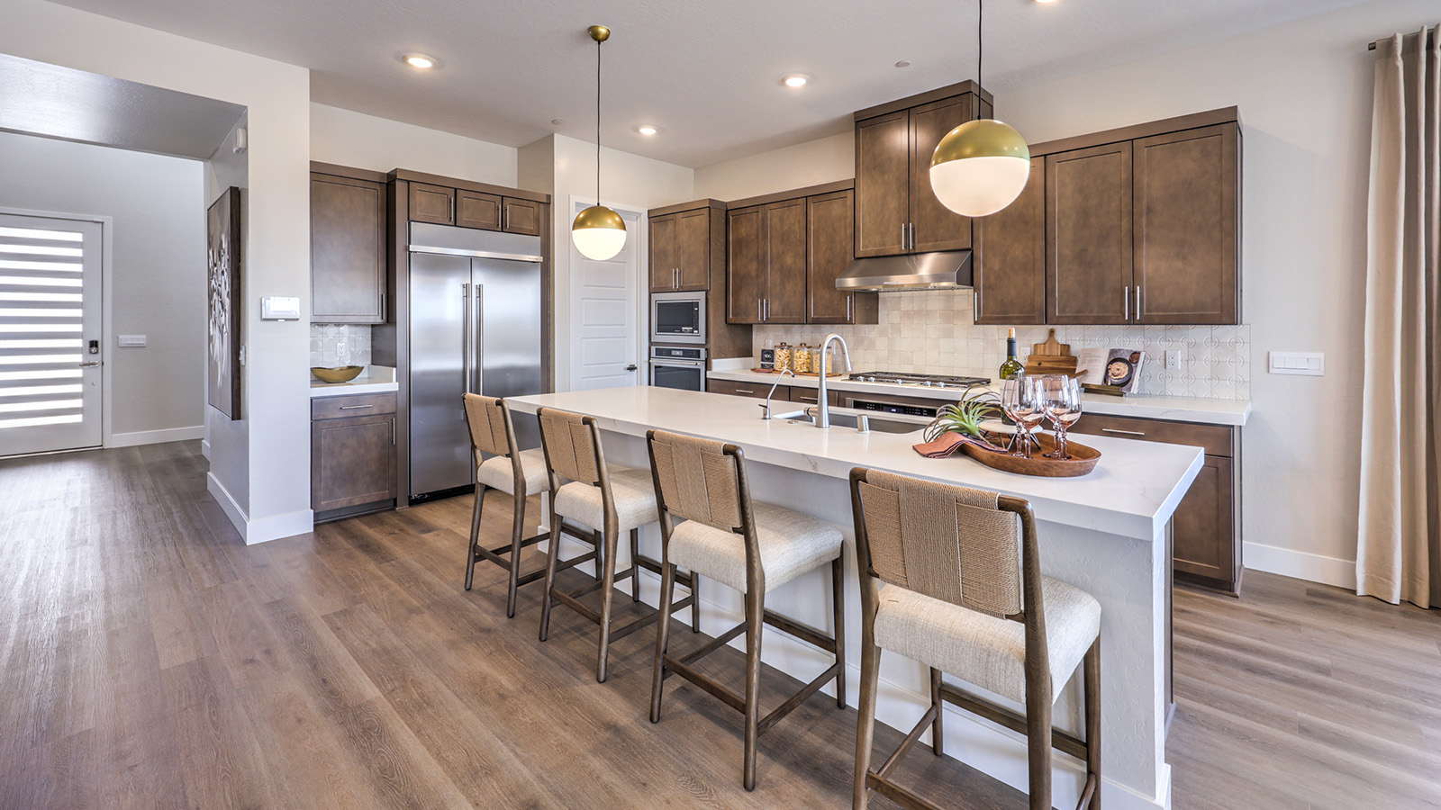Our 4418 model kitchen in the Heartland Summit Community with brown shaker style cabinets, quartz countertops, a kitchen island, 5-burner cooktop, large pantry, and Whirlpool Stainless Steel appliances.