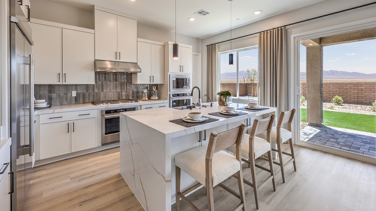 Our 3774 model kitchen in the Heartland Summit Community with white shaker style cabinets, granite countertops, a kitchen island, 5-burner cooktop, large pantry, and Whirlpool Stainless Steel appliances.