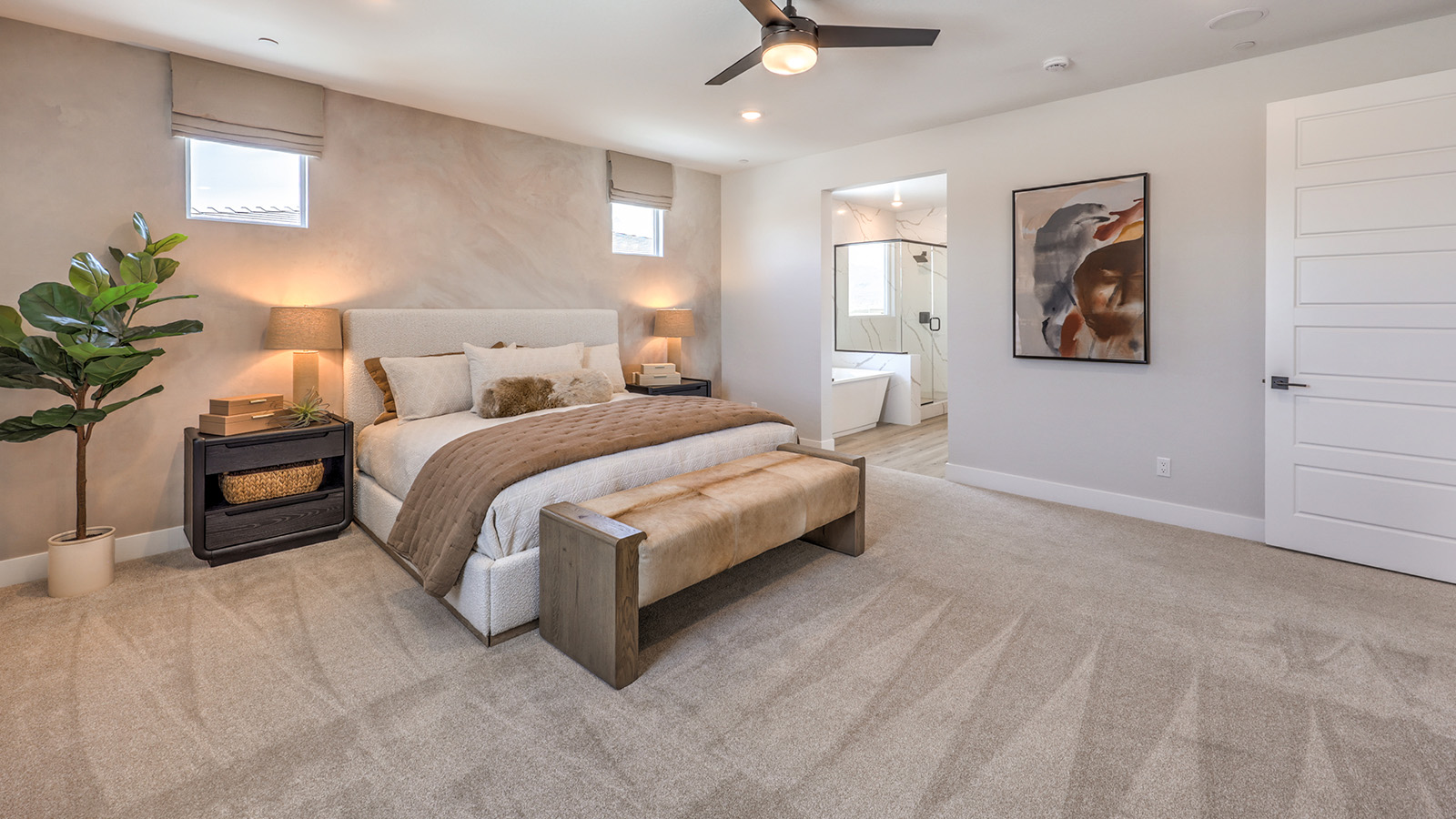 The Bedroom One Suite in our Heartland Summit 3774 model with carpet flooring, large windows, and a ceiling fan with a light kit.