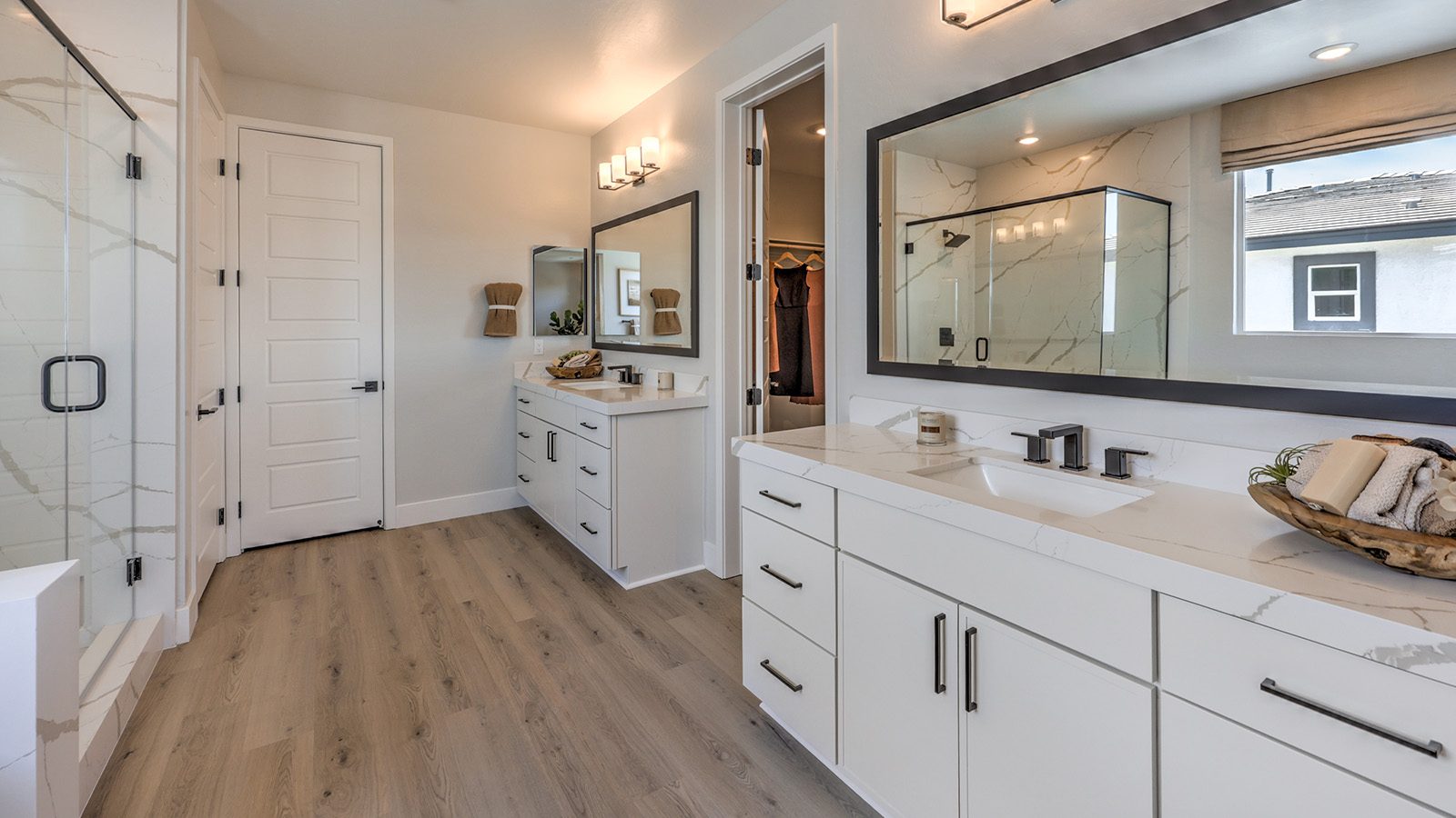 Attached to the Bedroom One Suite, our 3774 model bathroom with granite countertops at both Bath Vanities, a walk-in closet, mirror, and white cabinets.