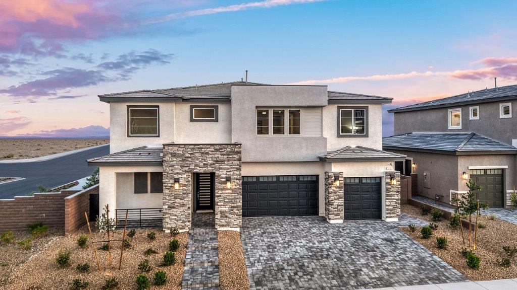 Our 4418 model home in the Heartland Summit community with grey and navy exterior paint schemes, a flat tile roof, front yard landscaping, paver walkways, and a four-car garage.