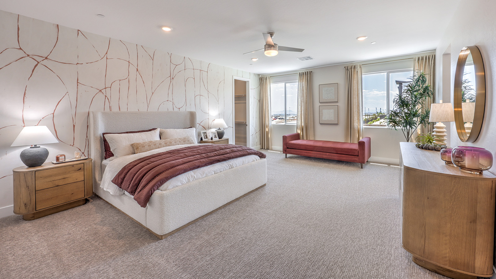The Bedroom One Suite in our Heartland Summit 4418 model with carpet flooring, large windows, and a ceiling fan with a light kit.