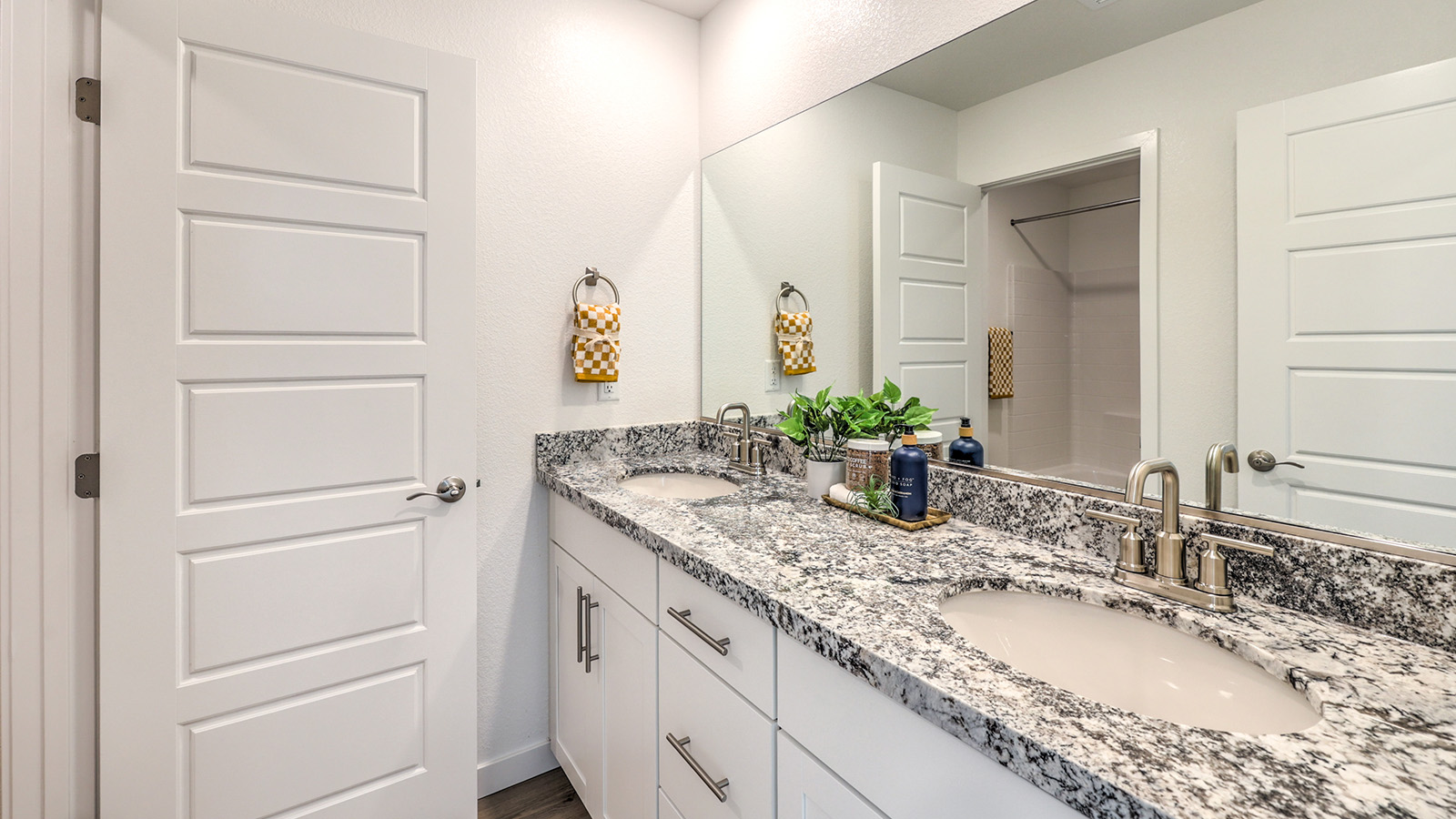 Bathroom Two in our Tropical Falls 2660 model with quartz countertops at the double Bath Vanity, a walk-in shower, mirror, and white cabinets.
