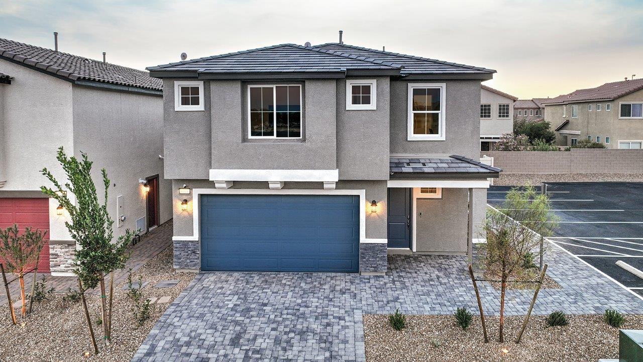 Our 2660 model home in the Tropical Falls community with blue and grey exterior paint schemes, a flat tile roof, front yard landscaping, 2-car garage, and paver walkways