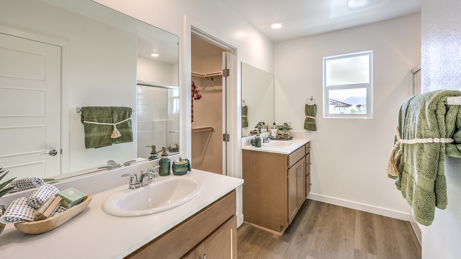 Attached to the Bedroom One Suite, our 1802 model bathroom with granite countertops at the double Bath Vanity, a walk-in shower, walk-in closet, mirror, and brown cabinets.