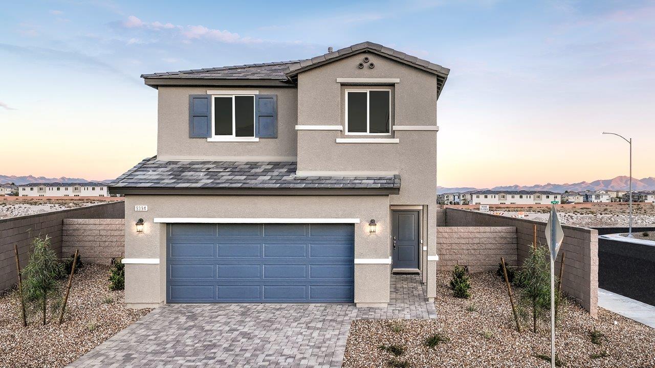 Our model home in the Meranto Bay community with tan and blue exterior paint schemes, a flat tile roof, front yard landscaping, and paver walkways.