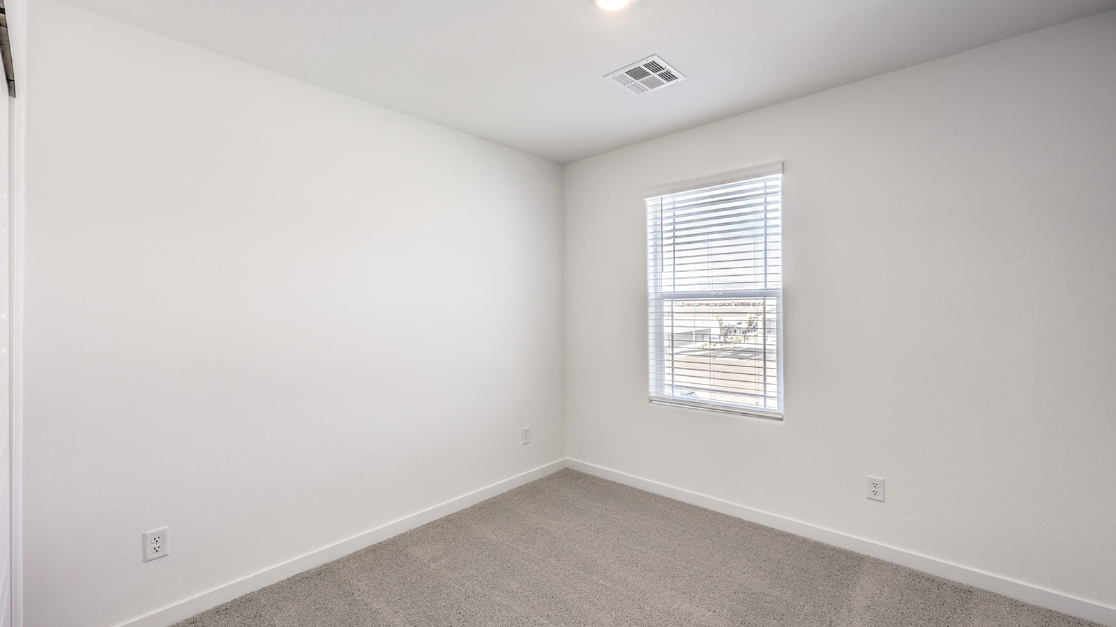 Bedroom Three in our Heartland Cottage 1550 model with carpet flooring, a sliding closet, and one window.