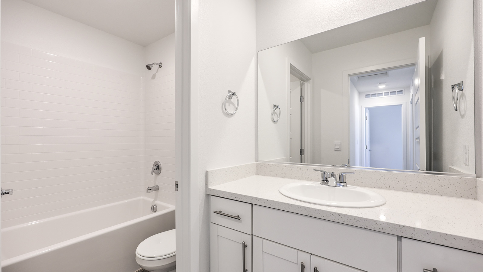 Bathroom Two in our Heartland Cottage 1550 model with granite countertops at the Bath Vanity, a walk-in shower, mirror, and white cabinets.