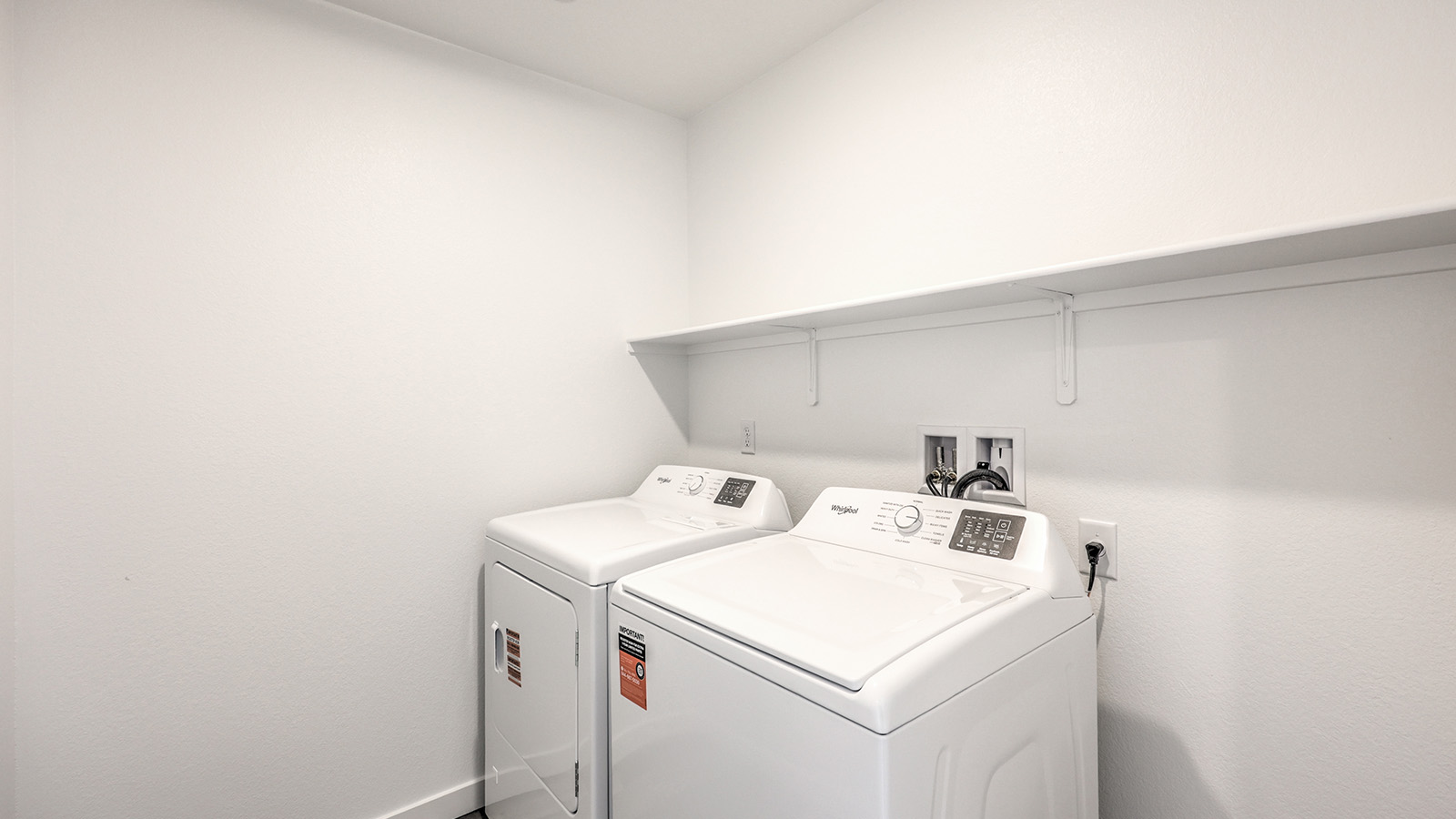 Our Heartland Cottage 1550 model laundry room with shelves and a washer and dryer.