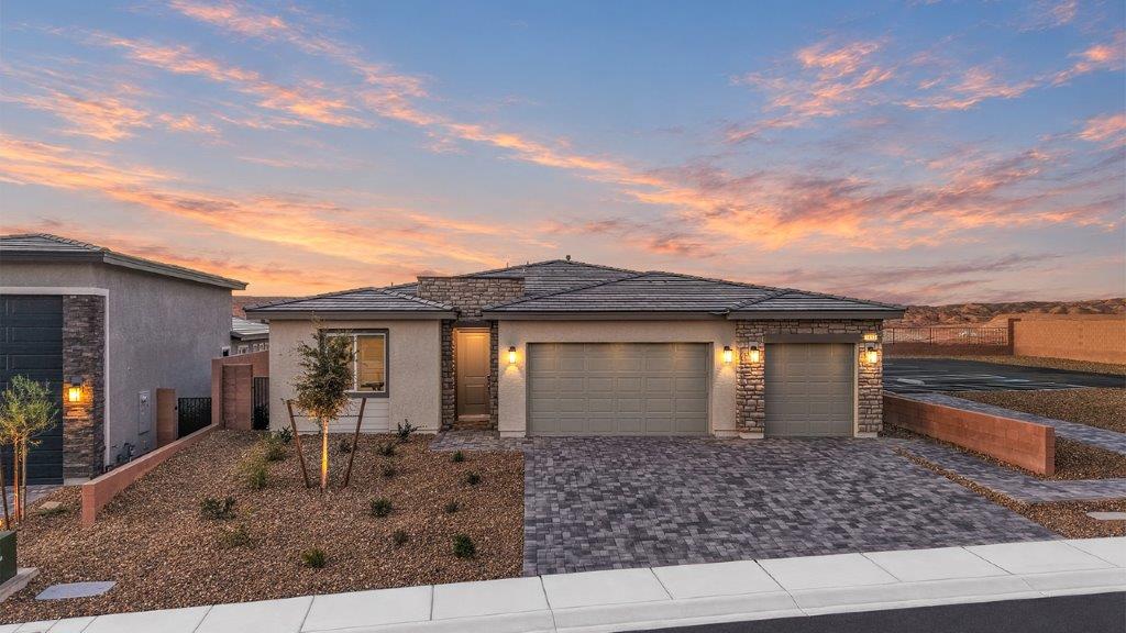 Our 2390 model home in the Majestic Hills community with gray and white exterior paint schemes, a flat tile roof, front yard landscaping, paver walkways, and a four-car tandem garage.