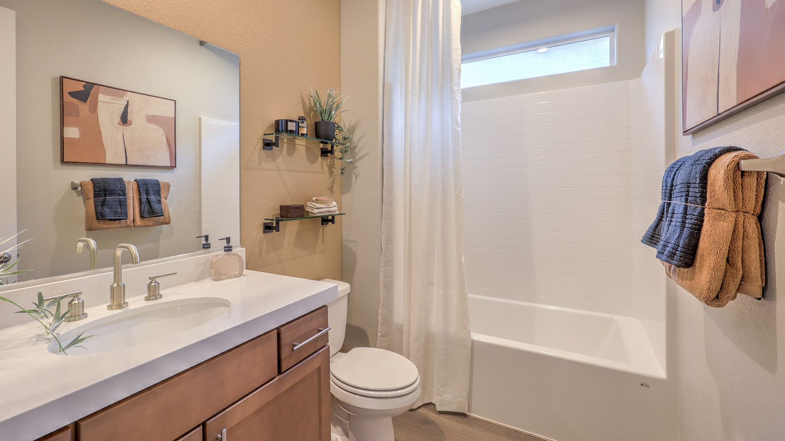 The Majestic Hills 2390 Plan Bathroom 2 featuring Luxury Vinyl Plank flooring, a granite countertop vanity with an undermount sink, and a combination tub and shower with white tile surround. A transom window above the shower provides natural light while maintaining privacy, making this bathroom a bright and functional space for daily use.