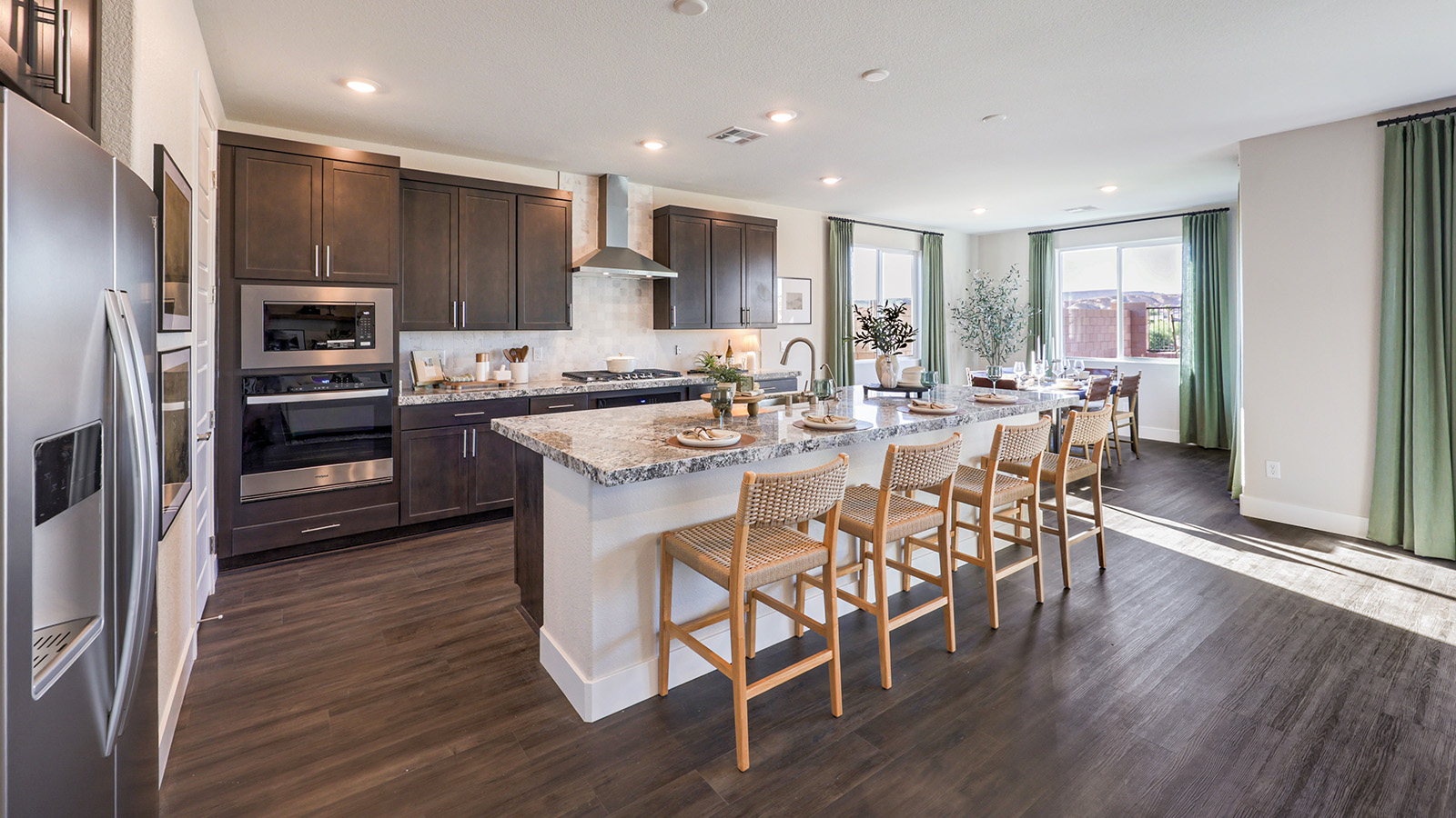 The Majestic Hills 2650 Plan Kitchen featuring Luxury Vinyl Plank flooring, granite countertops with a large center island, and a herringbone tile backsplash. Equipped with Whirlpool Stainless Steel Appliances including a 5-burner cooktop, built-in microwave, and dishwasher, this kitchen is designed for both functionality and modern style.
