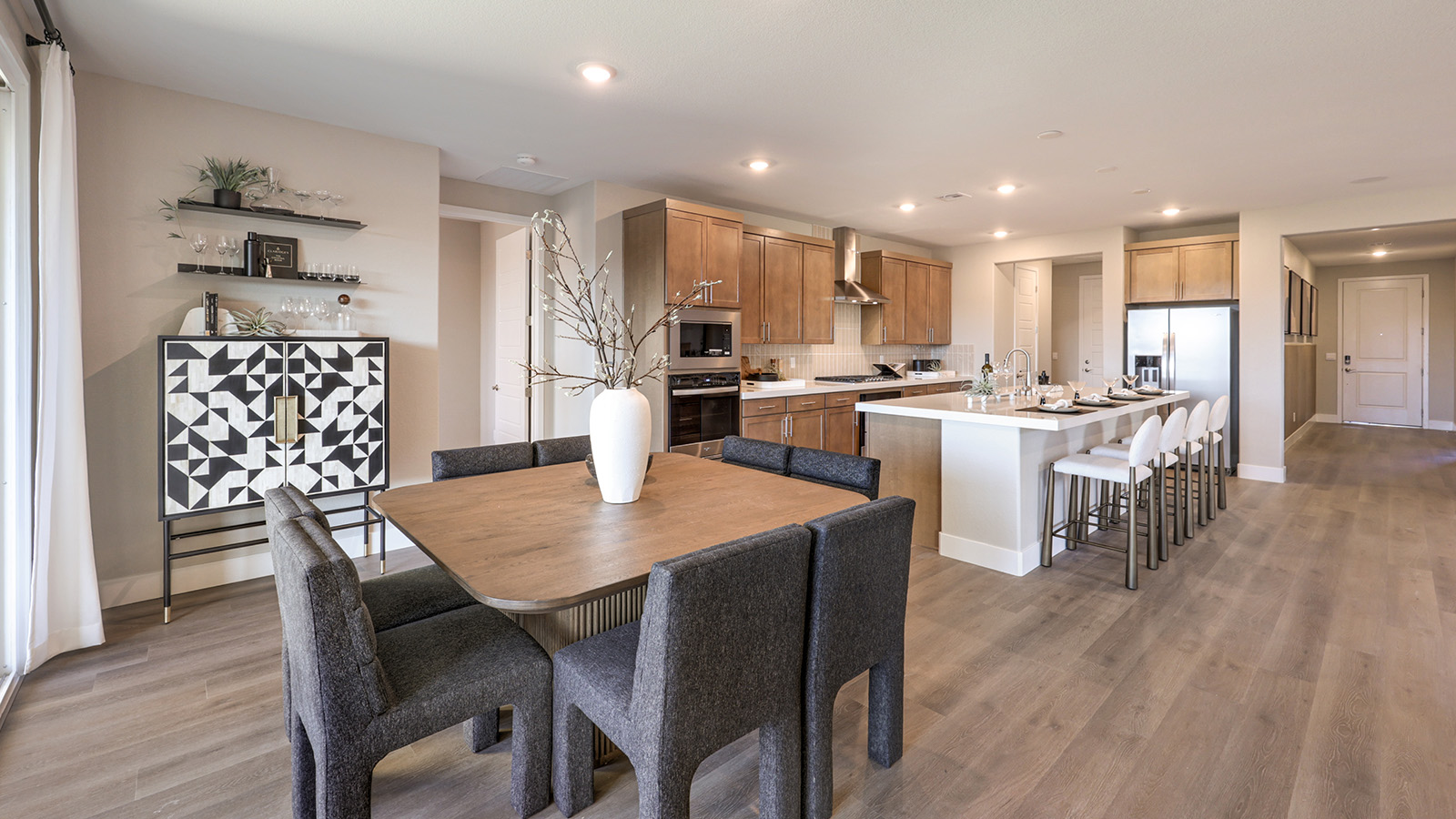The Majestic Hills 2390 Plan Dining Room featuring Luxury Vinyl Plank flooring, a large front-facing window that brings in natural light, and an open layout connected to the main entry, offering a versatile space for dining or entertaining.