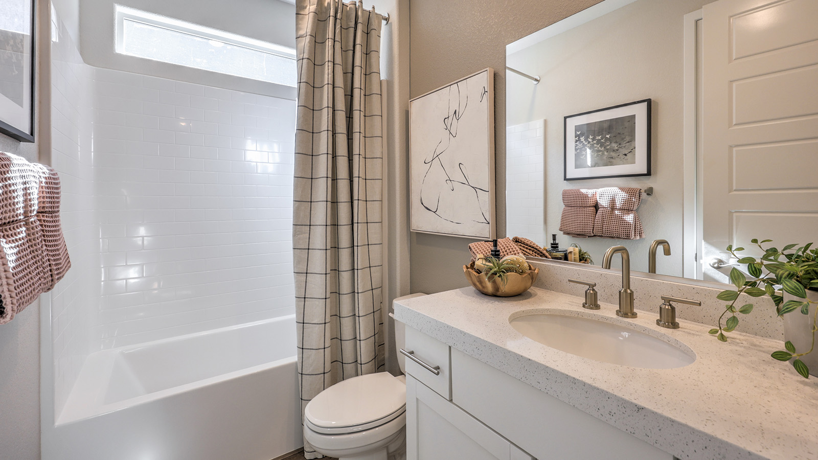 Bathroom Two in our Majestic Hills 1617 model with quartz/marble fusion countertops at the Bath Vanity, a walk-in shower, mirror, and white cabinets.