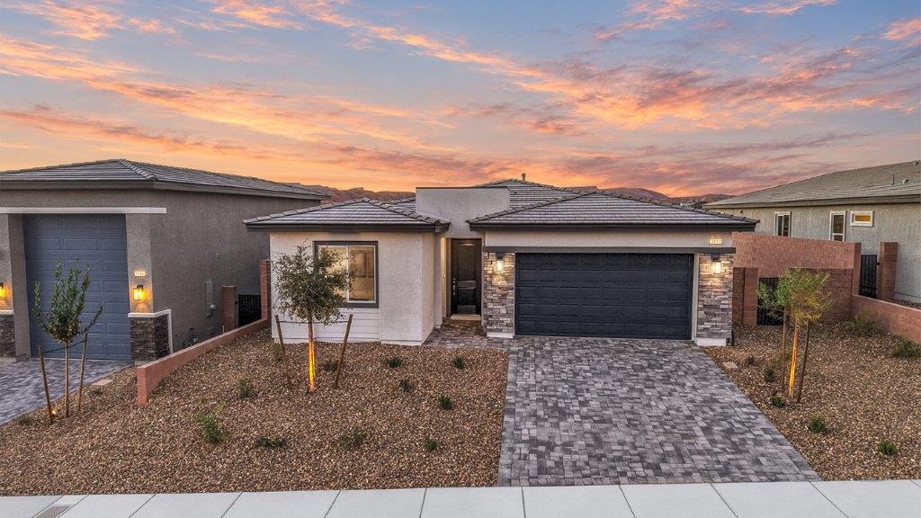 Our 1617 model home in the Majestic Hills community with black and white exterior paint schemes, a flat tile roof, front yard landscaping, paver walkways, and a two car garage.