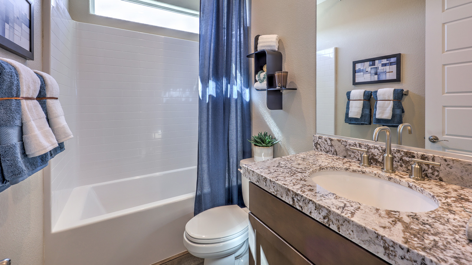 Bathroom Two in our Majestic Hills 1870 model with quartz/marble fusion countertops at the Bath Vanity, a walk-in shower, mirror, and white cabinets.