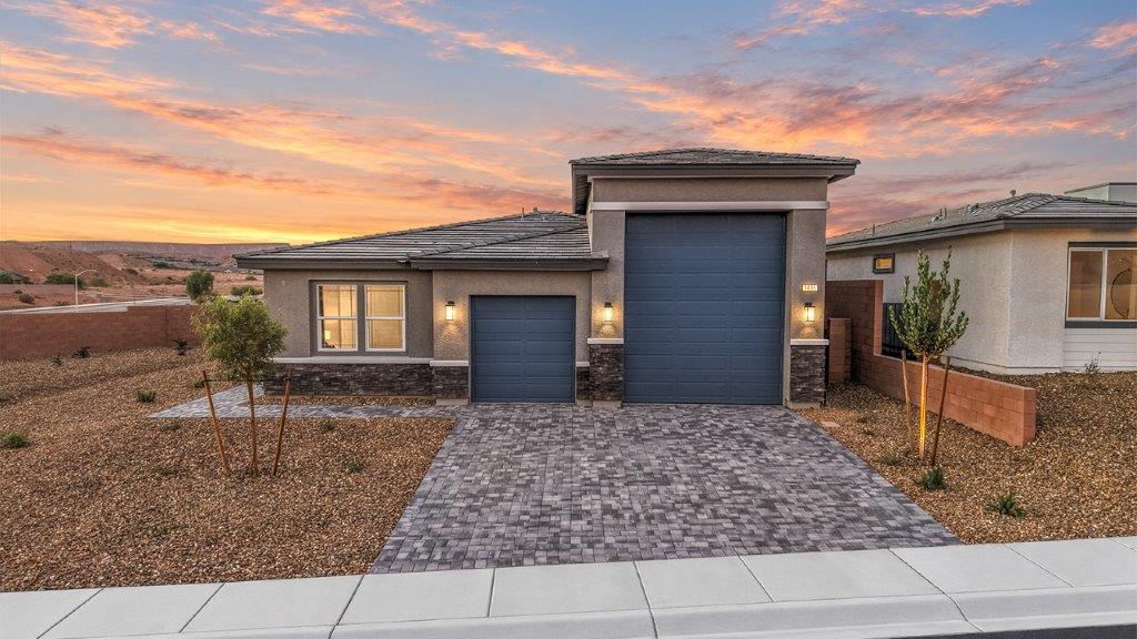 Our 1870 model home in the Majestic Hills community with blue and grey exterior paint schemes, a flat tile roof, front yard landscaping, paver walkways, and a two car garage.