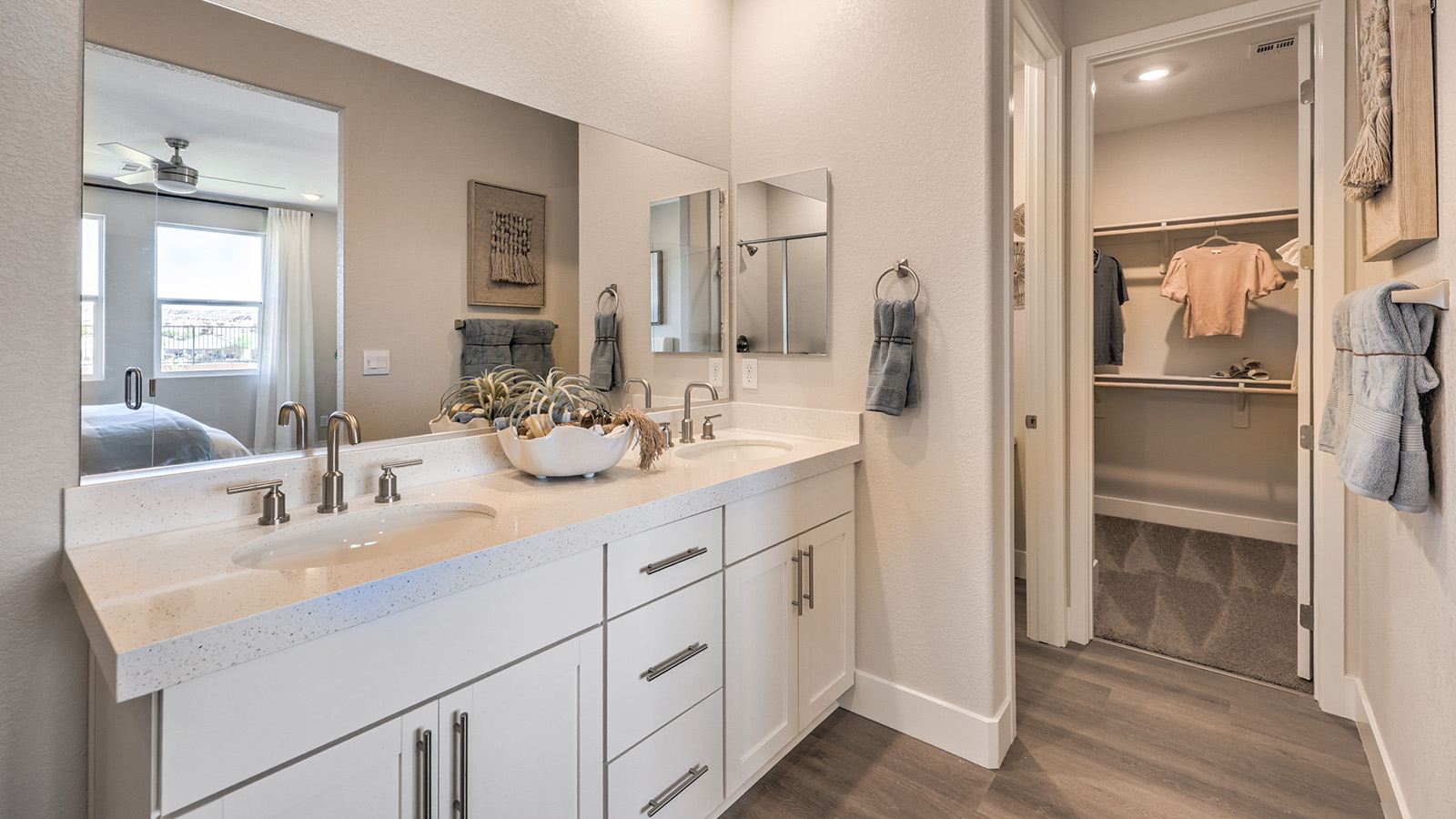 Attached to the Bedroom One Suite, our 1617 model bathroom with quartz/marble fusion countertops at the double Bath Vanity, a walk-in shower, walk-in closet, mirror, and white cabinets.