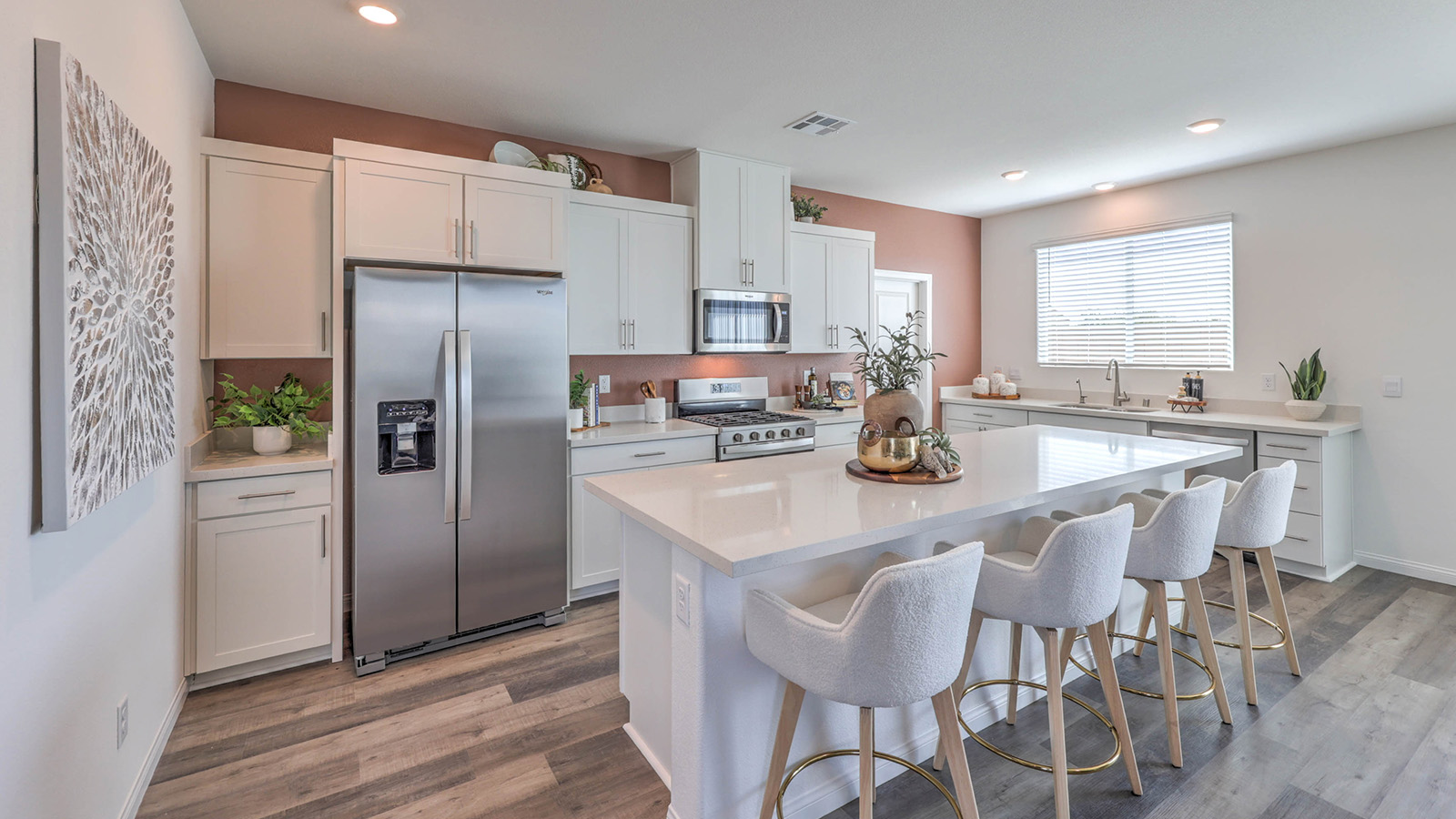 Our 3000 model kitchen in the Sky Falls Community with white shaker style cabinets, quartz slab countertops, a kitchen island, window, and Whirlpool Stainless Steel appliances.