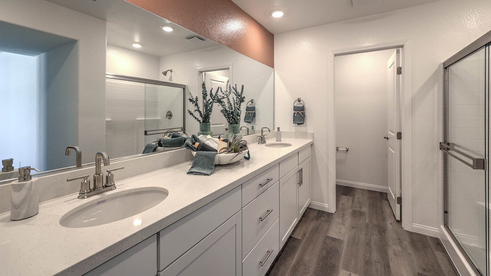 Attached to the Bedroom One Suite, our 3000 model bathroom with quartz countertops at the double Bath Vanity, a walk-in shower, walk-in closet, linen closet, mirror, and white cabinets.