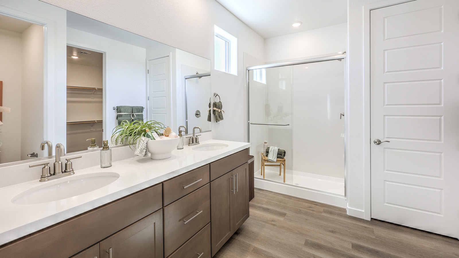 Attached to the Bedroom One Suite, our 2660 model bathroom with quartz countertops at the double Bath Vanity, a walk-in shower, walk-in closet, mirror, and white cabinets.