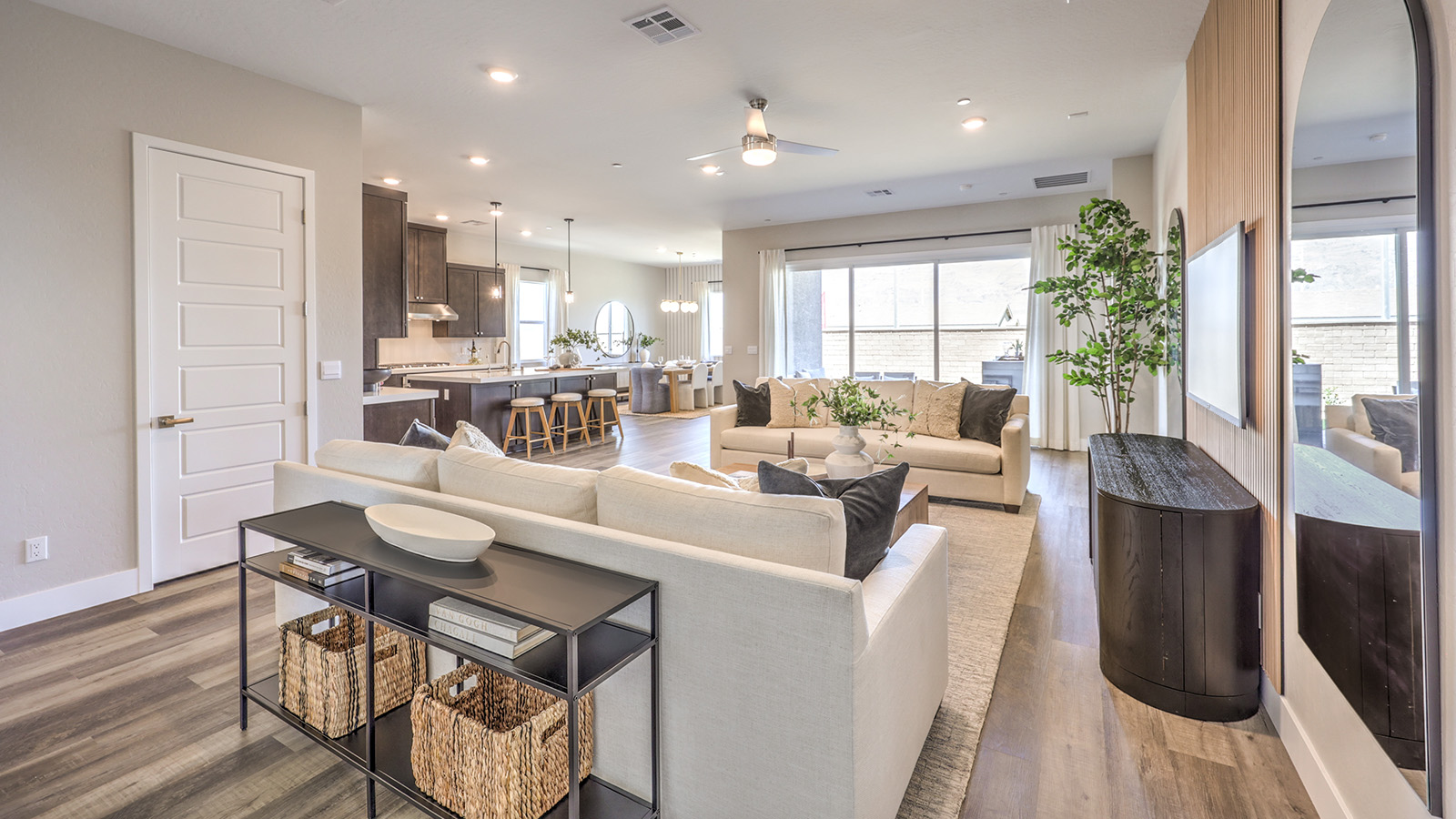 The great room in our Heartland Manor 2538 Plan features luxury vinyl plank flooring, an open-concept layout, and large windows that bring in natural light. The space flows seamlessly into the kitchen, creating a connected and spacious living area. A ceiling fan is centrally located, and sliding glass doors provide easy access to the backyard.