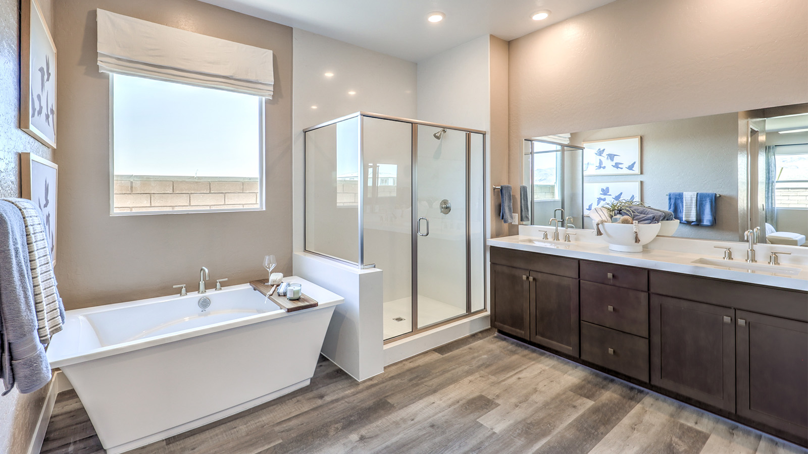 The main bathroom in our Heartland Manor 2538 Plan features luxury vinyl plank flooring, a spacious vanity with quartz or granite countertops, and dual sinks. A large mirror enhances the open feel of the space, while a window provides natural light. The bathroom connects to the main bedroom, offering both style and functionality.