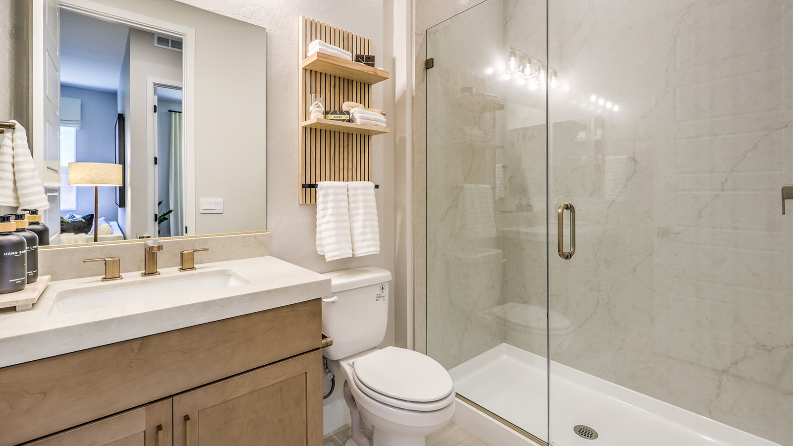 The MultiGEN bathroom in our Heartland Manor 2754 Plan features luxury vinyl plank flooring, a vanity with quartz or granite countertops, and a spacious walk-in shower with a glass enclosure. A large mirror enhances the space, while modern fixtures add style and functionality. Designed for convenience, this private bathroom is part of the MultiGEN suite, offering comfort and independence.