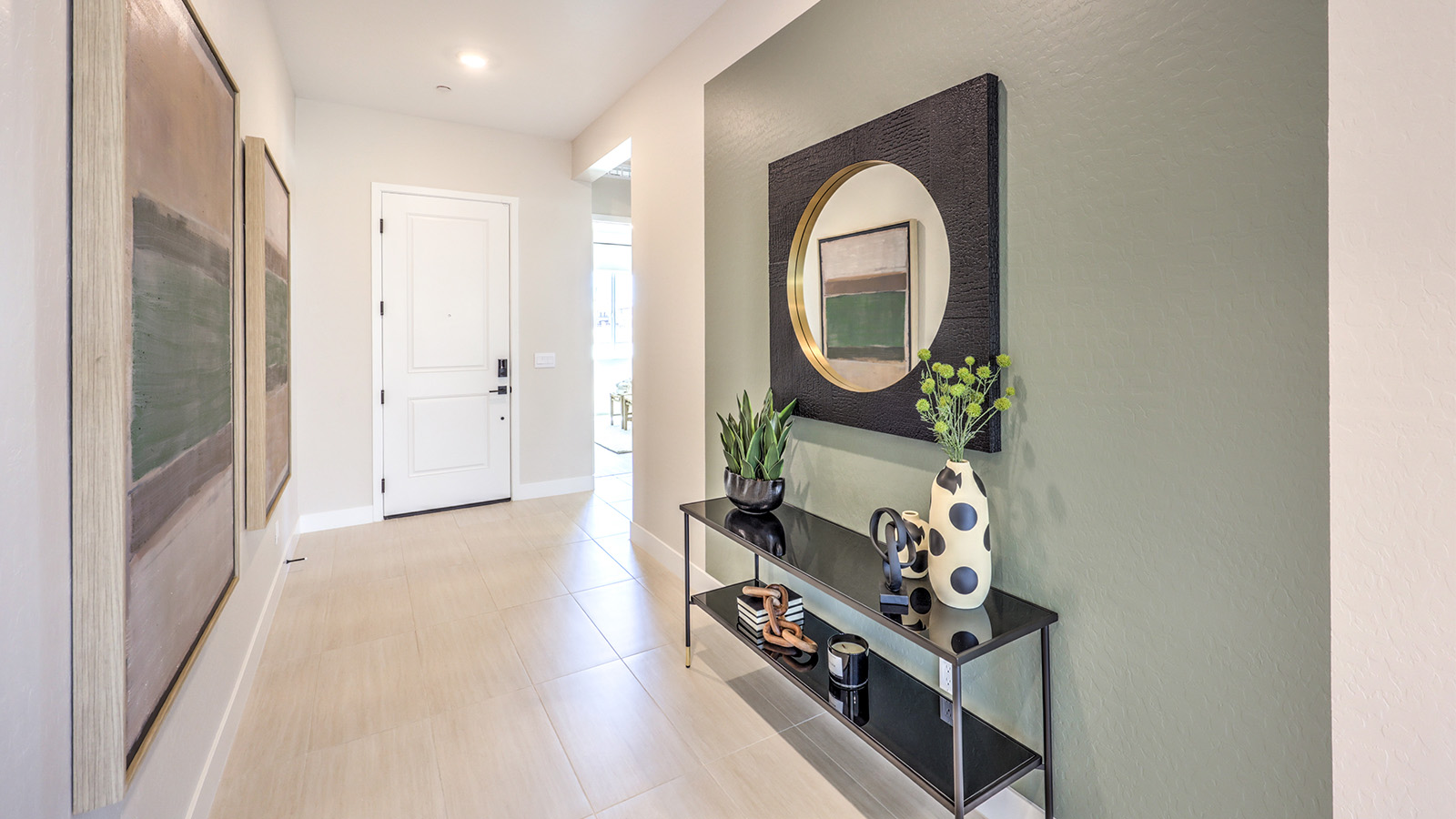 A modern home entrance with 9-foot flat ceilings and luxury vinyl plank flooring. The hallway leads to an open living area with large windows. To the right, are three doorways which provide access to two bedrooms and a bathroom.