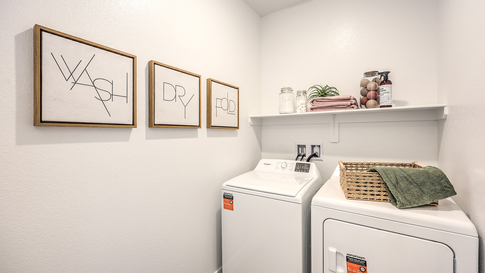 Our Serenity 2660 model laundry room with shelves and a washer and dryer.